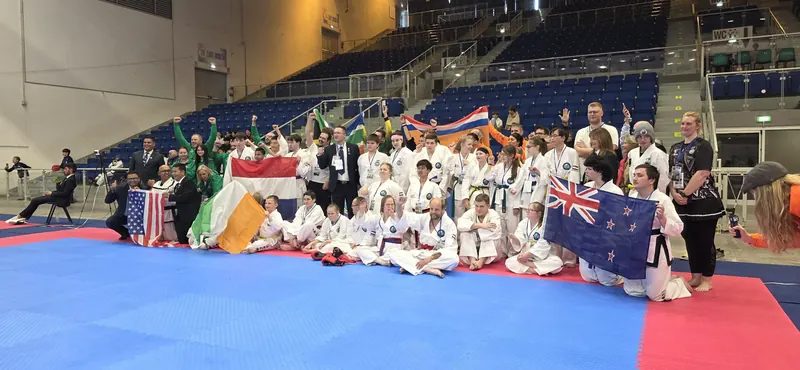 Athletes from many nations, including New Zealand, celebrate with their flags at the World Championships in Italy